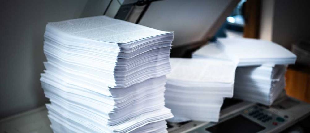 Ein Papierberg türmt neben dem Scanner
