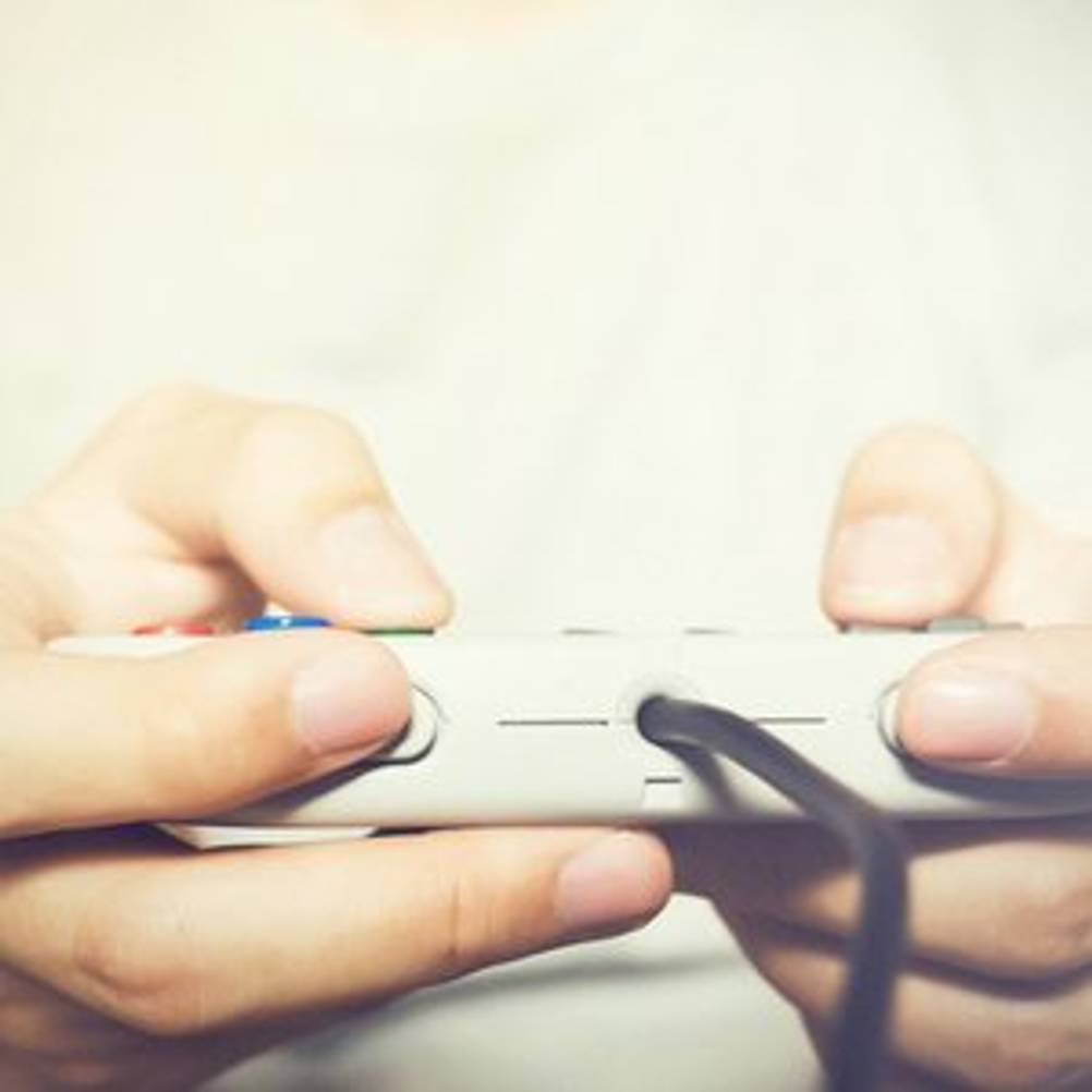 Junger Mann, der mit einem Controller ein Spiel steuert