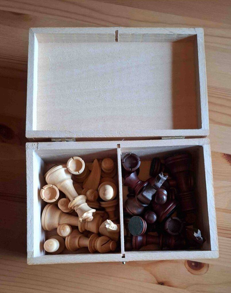Ein Set Schachfiguren im Test sind in einer Holzkiste aufbewahrt.