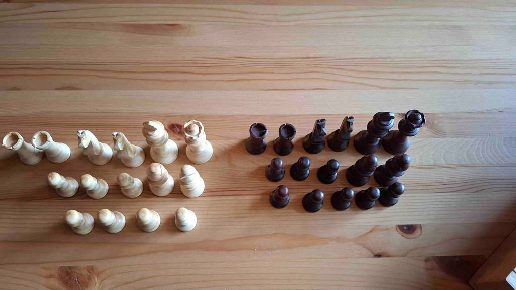 Blick von oben auf Schachfiguren, die zum testen auf einem Holztisch stehen.