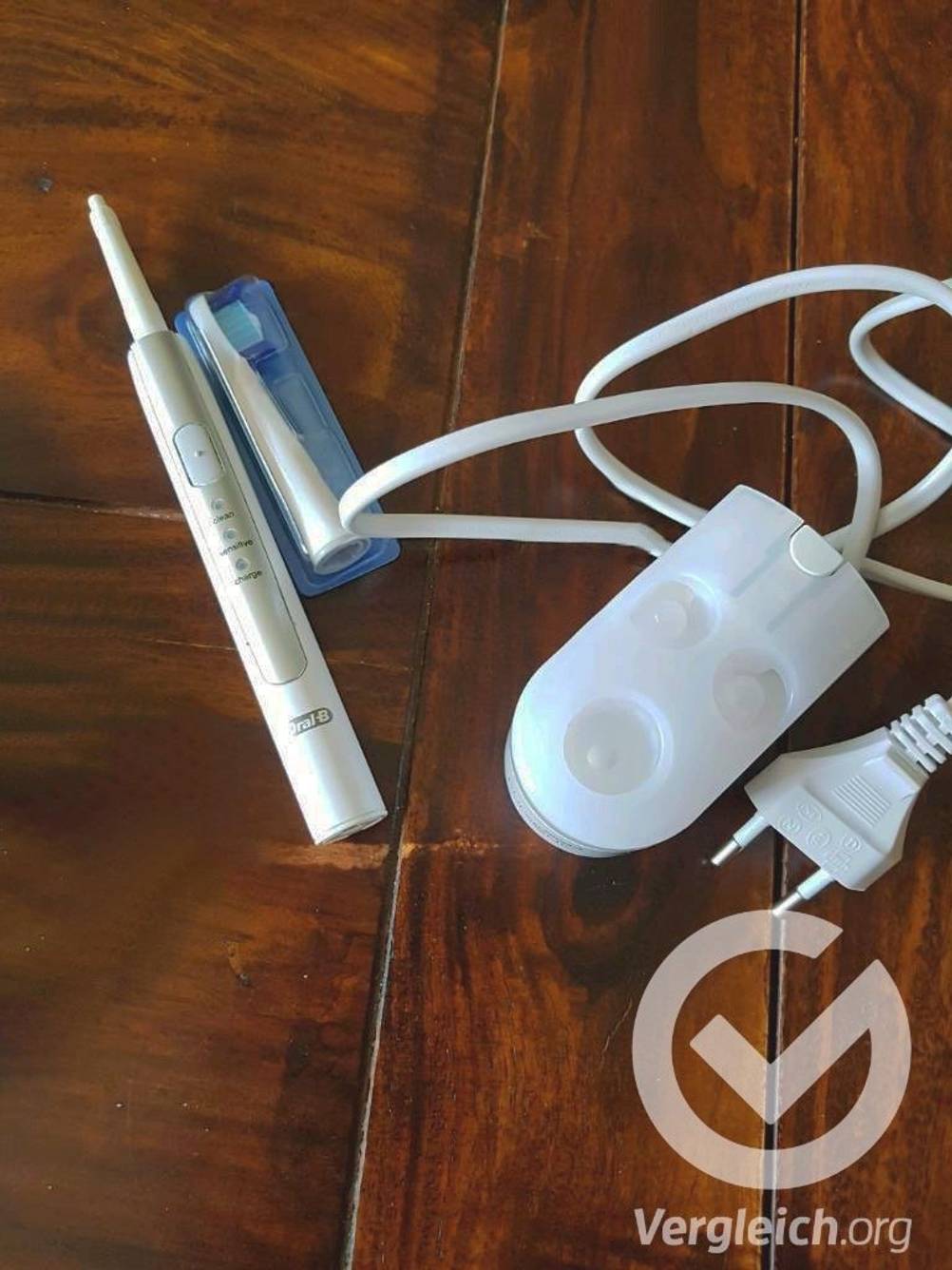 Eine Oral-B Schallzahnbürste im Test liegt neben dem Ladegerät und einem Ersatzputzkopf.