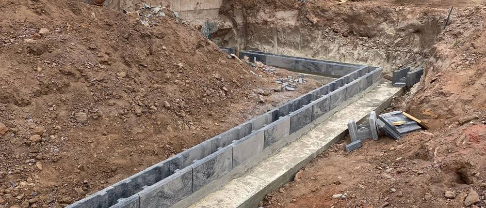 Die erste Schalsteinreihe wird auf das getrocknete Betonfundament auf Mörtel gelegt.