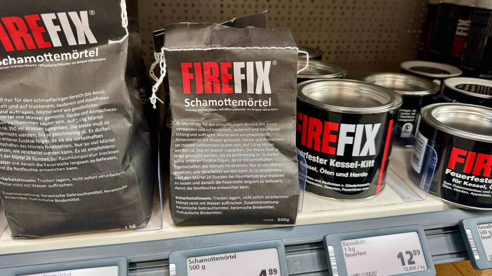 In einem Verkaufsregal neben anderen Produkten steht eine Packung des Schamottemörtels im Test.
