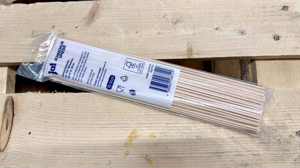 Eine Packung der getesteten Schaschlikspieße liegt mit der Rückseite nach oben auf einer Holzpalette.