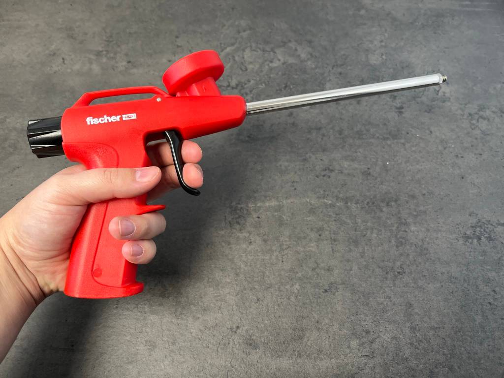 Schaumpistole im Test: Das Modell 62400 von Fischer (rot) wird in der Hand gehalten vor einem dunkelgrauen Hintergrund.