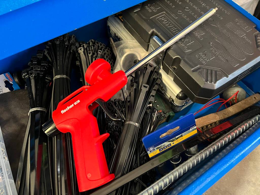 Schaumpistole im Test: Hier liegt sie mit Kabelbindern und einigen Werkzeugen in einer blauen Eurobox.