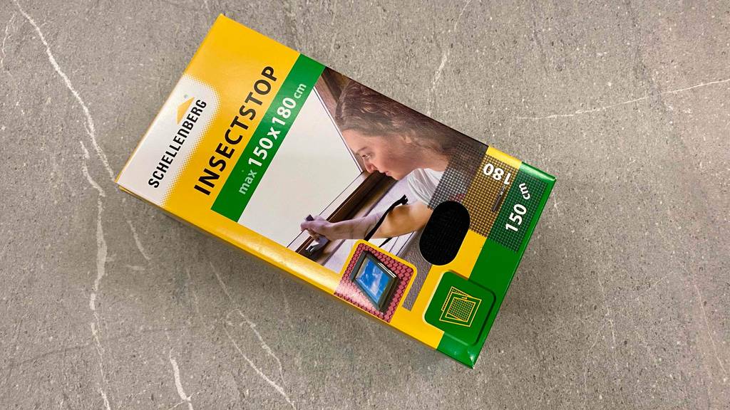 Der Verpackungskarton eines getesteten Fliegengitters liegt quer auf einem Steinboden.