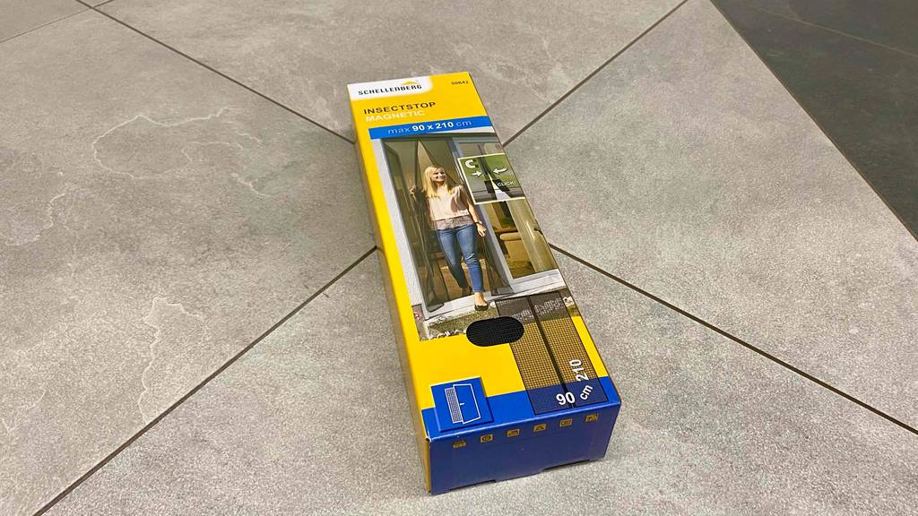 Die Verpackung eines getesteten Fliegengitters mit Magnet liegt auf einem Fliesenboden.