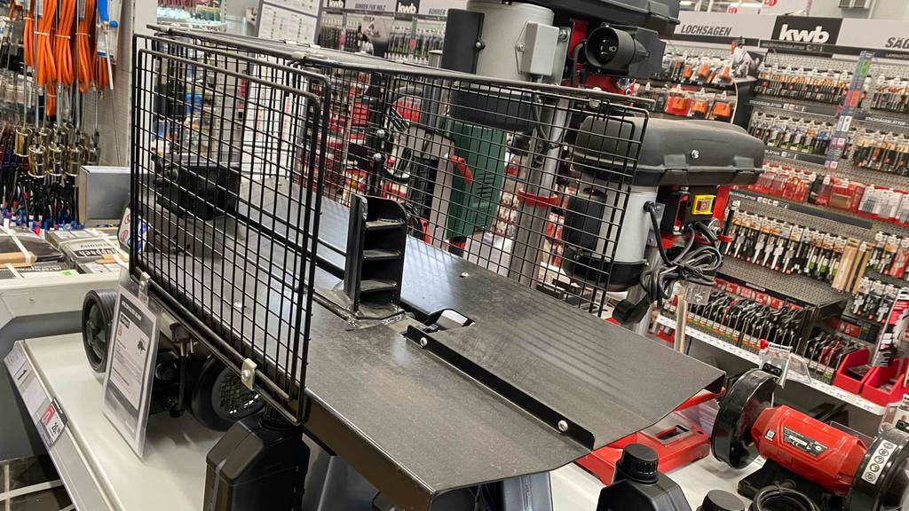 Holzspalter-Test: In einem Baumarkt steht ein elektrischer Holzspalter auf einem Ausstellungsregal inmitten anderer Werkzeuge.