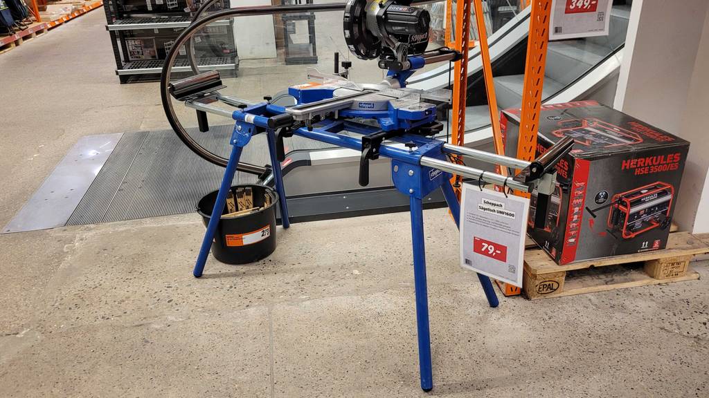 Ein Kappsägen-Untergestell steht zum Testen mit Verkaufsschild vor einer Rolltreppe.