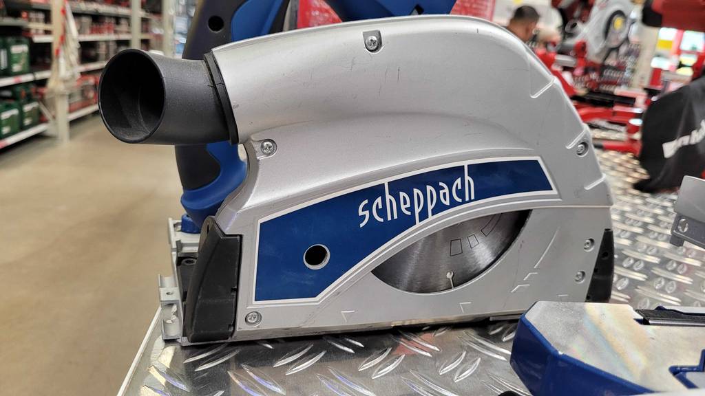 Seitenansicht auf die silberfarbene Verkleidung inklusive Scheppach-Schriftzug einer Tauchsäge mit Führungsschiene im Test innerhalb eines Baumarkts.