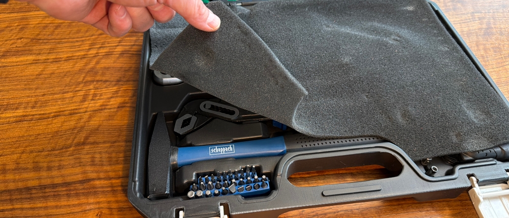 Eine Hand nimmt die Schaumstoffabdeckung von der Innenseite des Scheppach WZK120