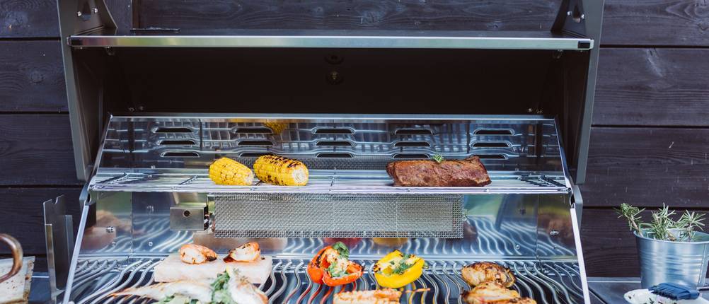 Schickling-Grill-Test: Ein geöffneter Grillwagen mit zwei Grillebenen, auf denen sich Grillgut befindet.