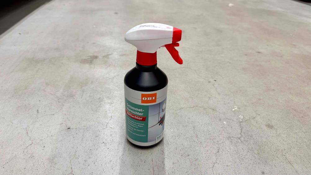 Eine Flasche des getesteten Schimmelsprays auf einem Betonboden von schräg oben.