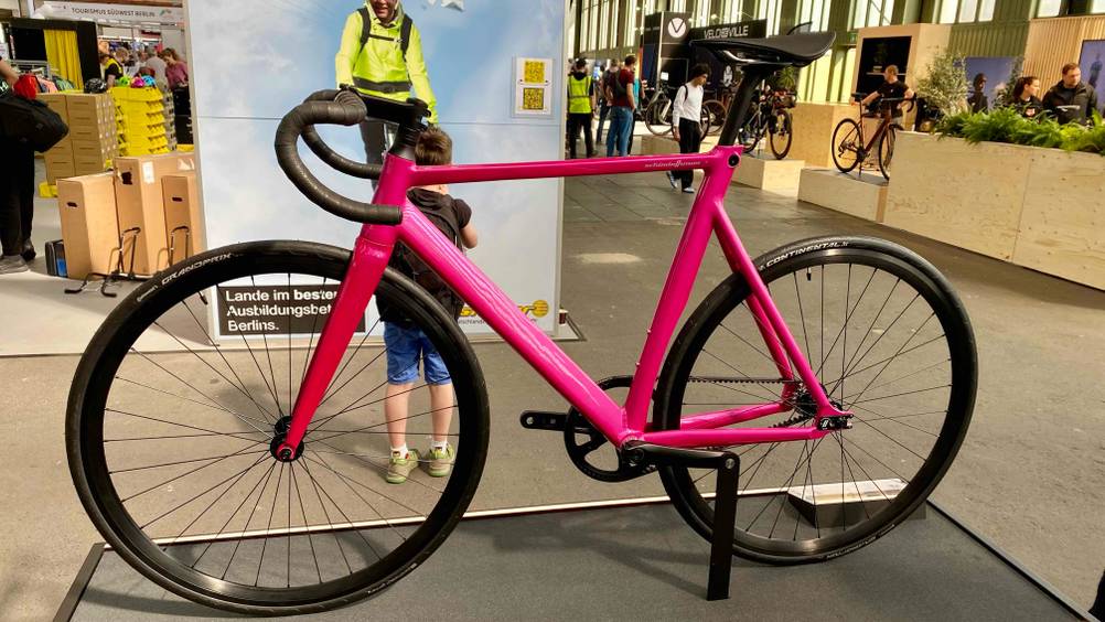 Singlespeed Bike Test: Ein pinkfarbenes Rad auf einem schwarzen Ständer von der Seite