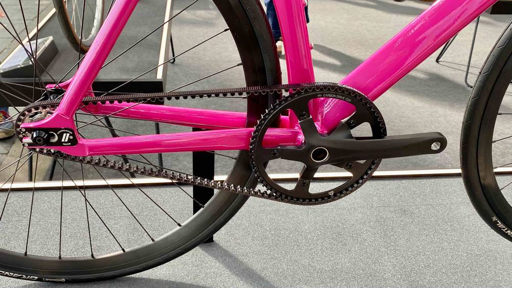 Singlespeed Bike Test: Nahaufnahme von Pedal und Kette eines Singlespeed Bike im Test mit pinkem Rahmen.