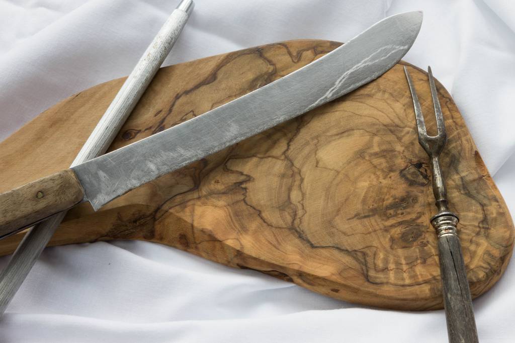 Schinkenhalter-Test: Ein Schinkenmesser, Schleifmesser und eine Gabel sind auf einem Holzbrett platziert. 