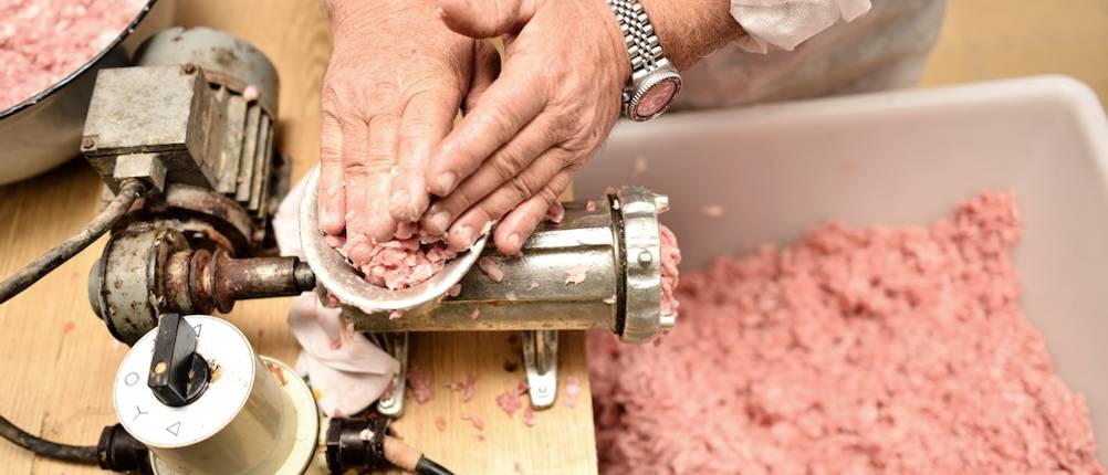 Wurstbrät im Test: Fleisch wird in einem Fleischwolf zerkleinert.