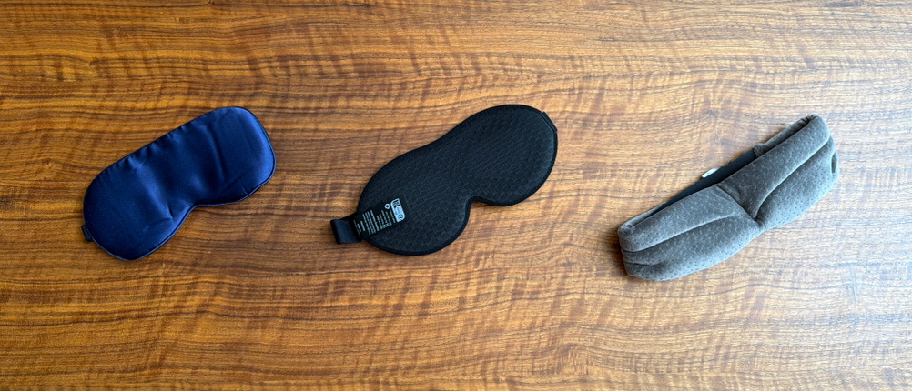 Drei Schlafmasken liegen nebeneinander auf einem Tisch.