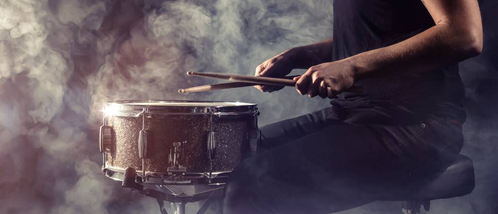 Schlagzeughocker im Test: Ein Schlagzeuger sitzt vor einer Snare auf einer Bühne mit Nebel.