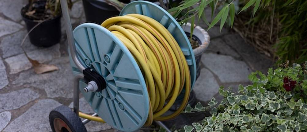 Schlauchwagen mit Schlauch getestet: Nahaufnahme einer blauen Schlauchtrommel mit einem gelben Gartenschlauch.