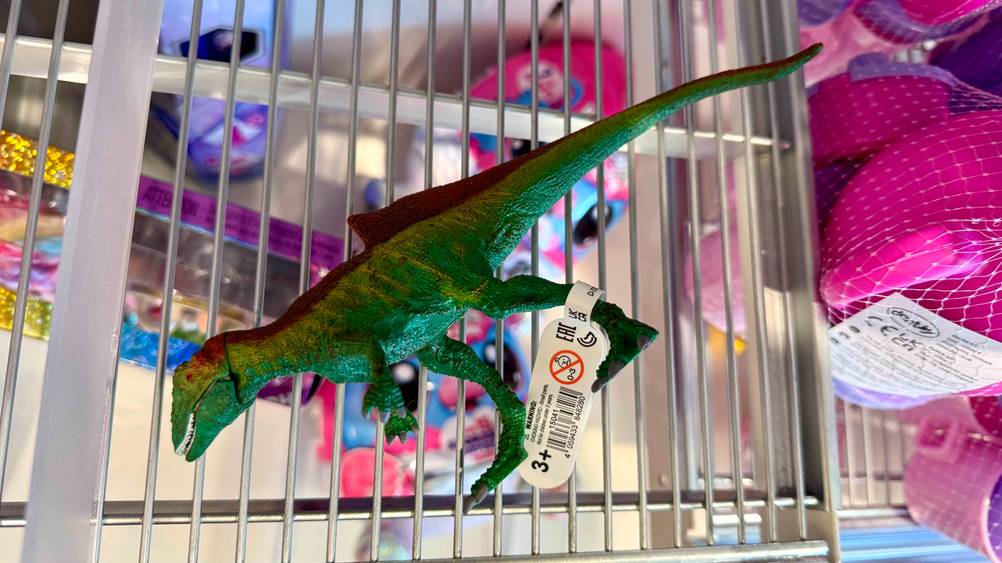 Auf einem Gitter liegt der getestete Schleich-Dinosaurier auf der Seite.