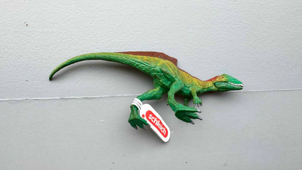 Ein getesteter Schleich-Dinosaurier auf der Seite liegend.