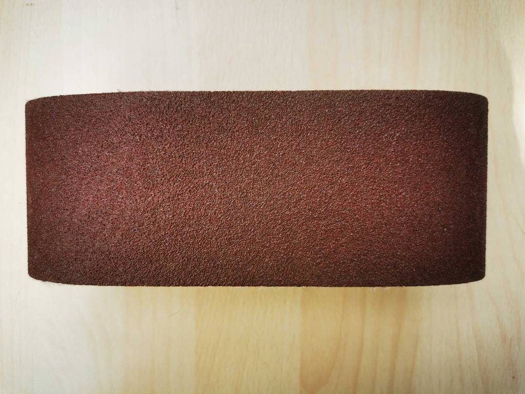 Ein Schleifband liegt zum testen auf einem Brett.