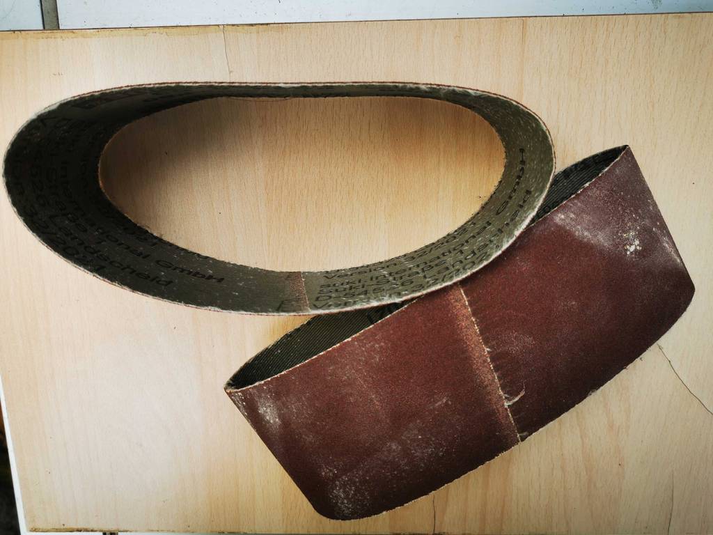Schleifband im Test: Blick von oben auf zwei Bänder, die auf einem Holzbrett liegen.