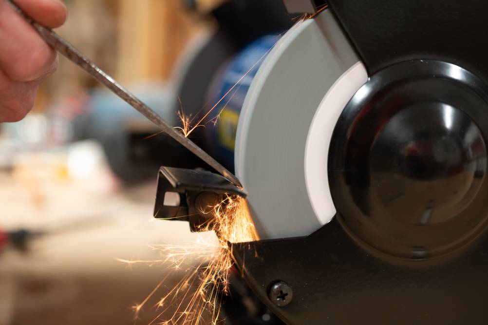 Schleifhilfe-Stechbeitel im Test: Ein Stechbeitel wird an einem Schleifbock geschliffen, wobei Funken sprühen.