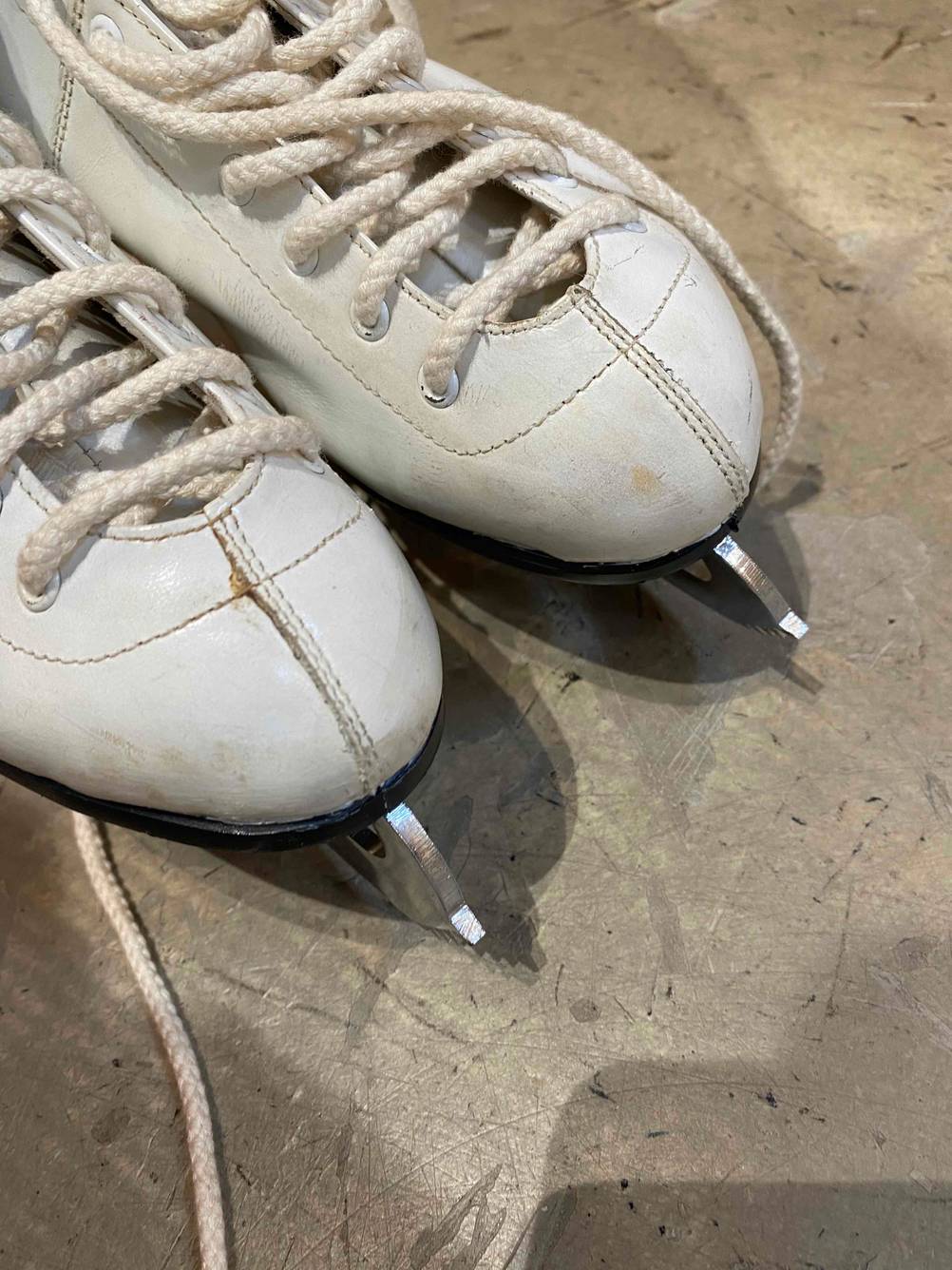 Schlittschuhe Damen getestet: Nahaufnahme der Kappen der Schuhe auf einem Betonboden.