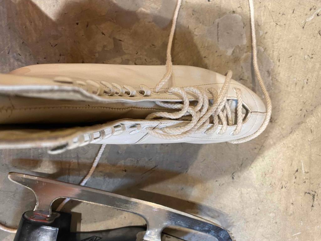 Auf dem Boden steht ein Paar getestete Schlittschuhe für Damen.