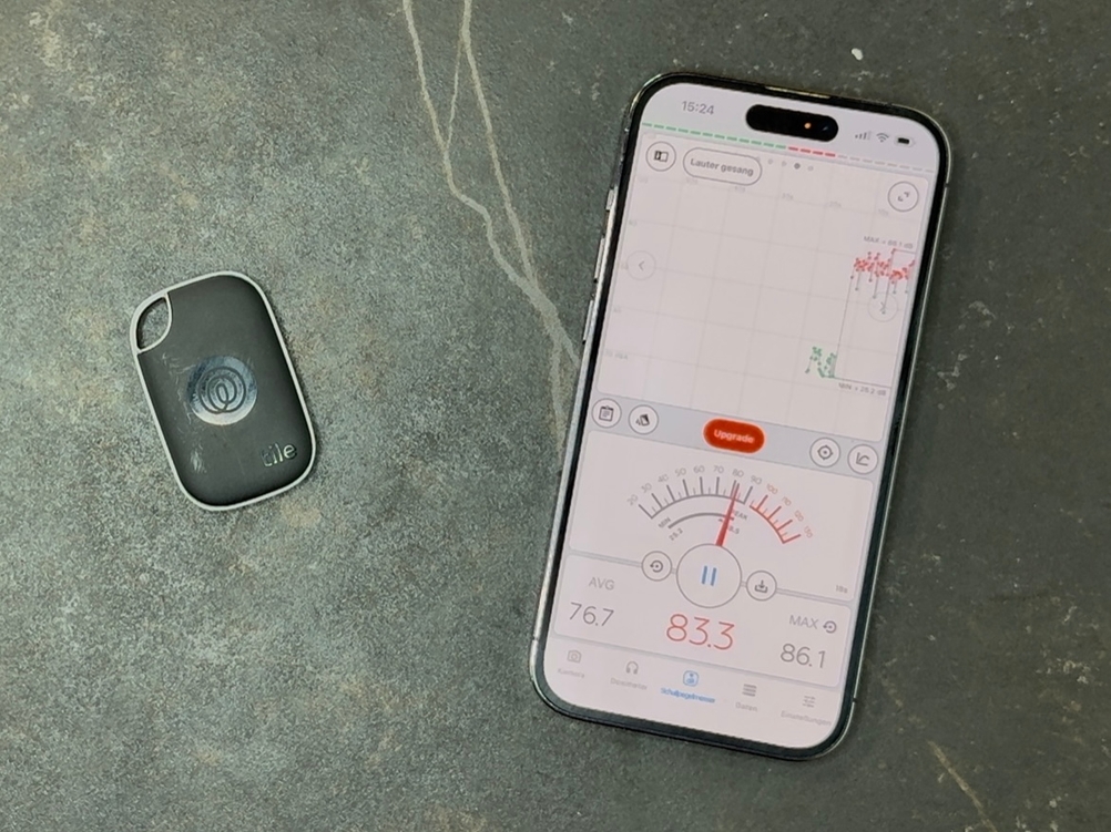 Ein Smartphone mit einer App zum Messen der Lautstärke liegt neben dem getesteten Schlüsselfinder von Tile.