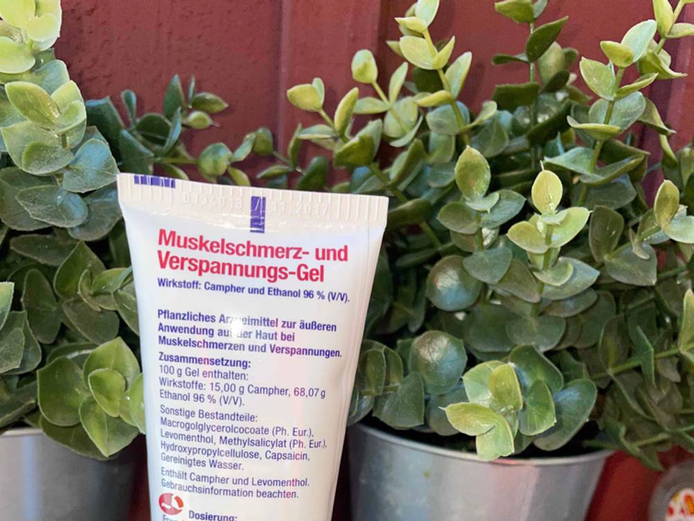 Nahaufnahme der Rückseite einer Tube Schmerzgel mit Informationen zur Zusammensetzung.