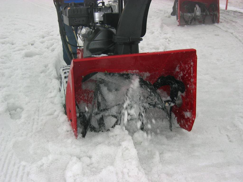 Eine rote Schneefräse im Test wird einen verschneiten Weg entlang geführt.
