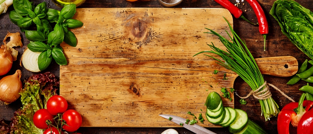Schneidebrett aus Holz mit Messer und Gemüse auf einem Tisch