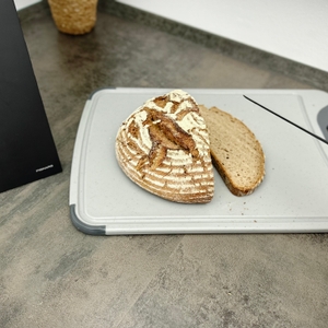 Ein rundes Bauernbrot liegt angeschnitten auf dem Silit-Schneidebrett 21.4223.5354. Zwei Scheiben wurden bereits abgeschnitten.