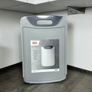 Das Silit-Schneidebrett 21.4223.5354 steht in Originalverpackung aufrecht auf einer Küchenarbeitsfläche.