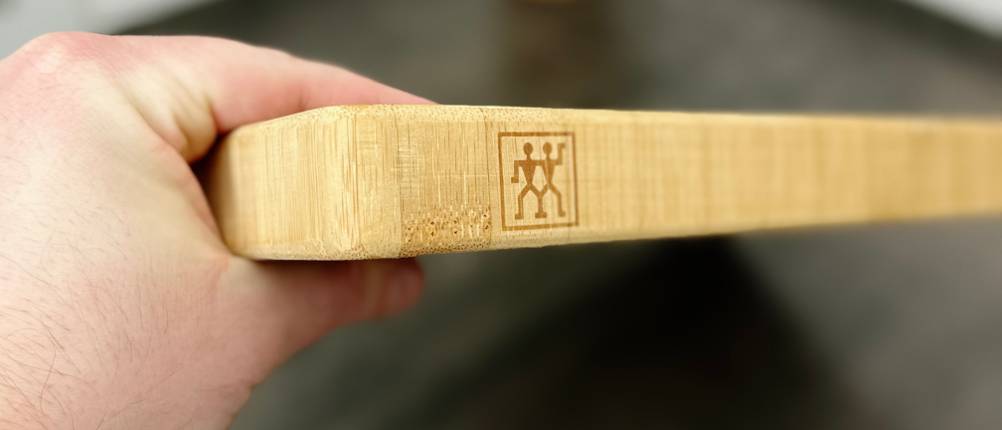 Eine Hand hält das Zwilling-Schneidebrett 30772-100 seitlich. Die Materialstärke ist deutlich erkennbar.
