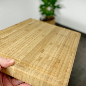 Eine Hand hält das Zwilling-Schneidebrett 30772-100 an der Seite. Die Oberfläche zeigt die typische Stirnholzstruktur.