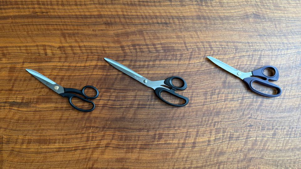 Drei Schneiderscheren liegen nebeneinander auf einem Tisch