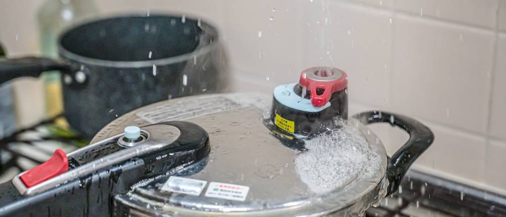 Die Sicherheit getestet: Aus dem Deckel eines Schnellkochtopfs tritt schäumendes Wasser aus.