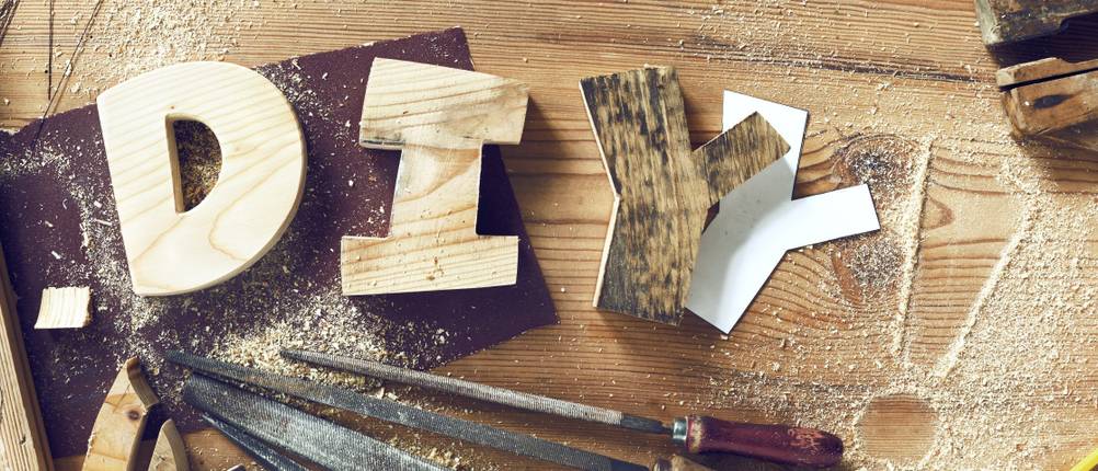 Der Schriftzug DIY als Holzklötze auf einer Werkbank