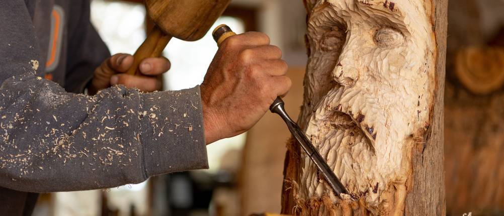 Schnitzholz-Test: Mann schnitzt eine Figur aus Holz.