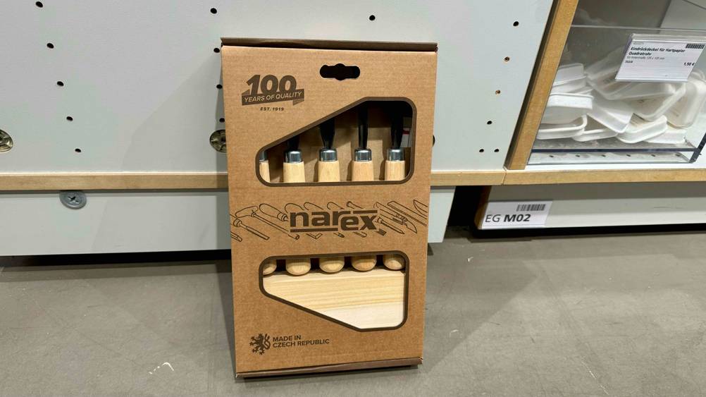 Getestet: Ein Schnitzwerkzeug in Originalverpackung lehnt an einem Regal.