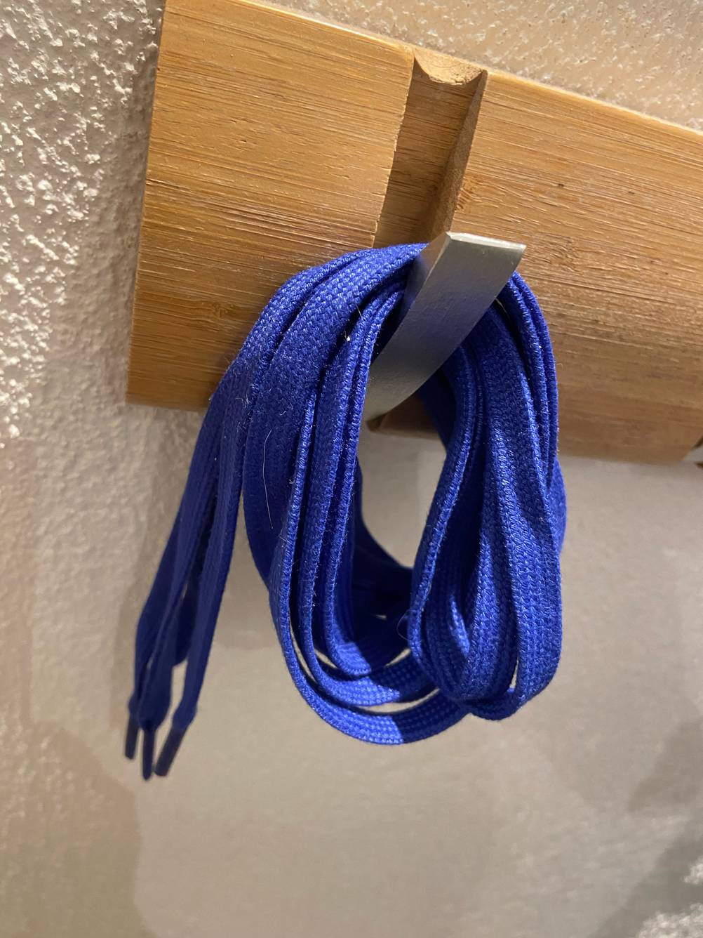 Im Test: Ein Paar blaue Schnürsenkel hängt an einem Garderobenhaken.