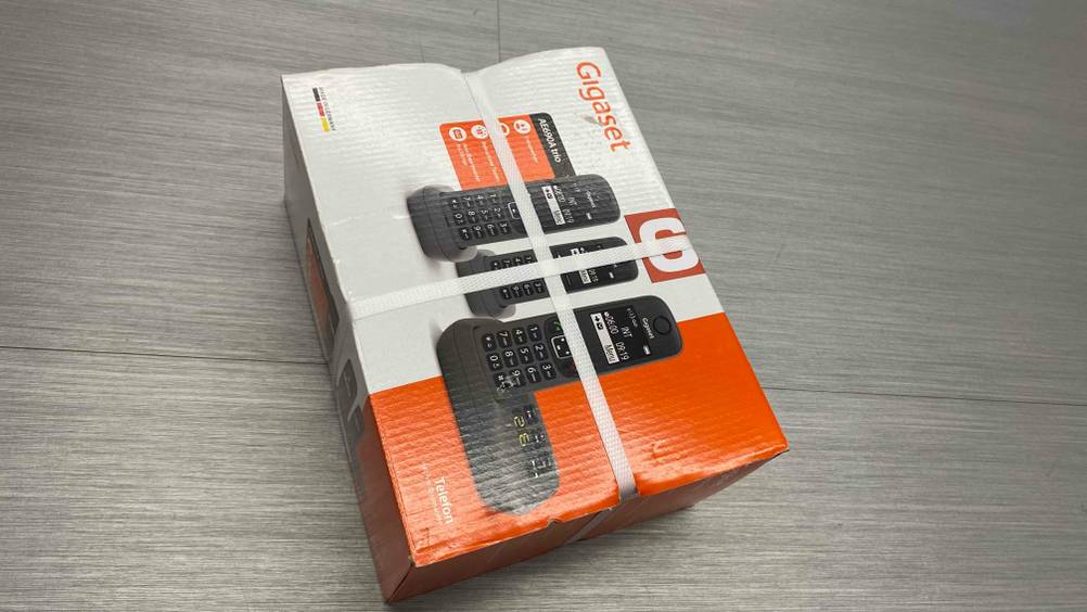 Ein getestetes Schnurloses Telefon-Trio in Originalverpackung auf einem graun Boden.