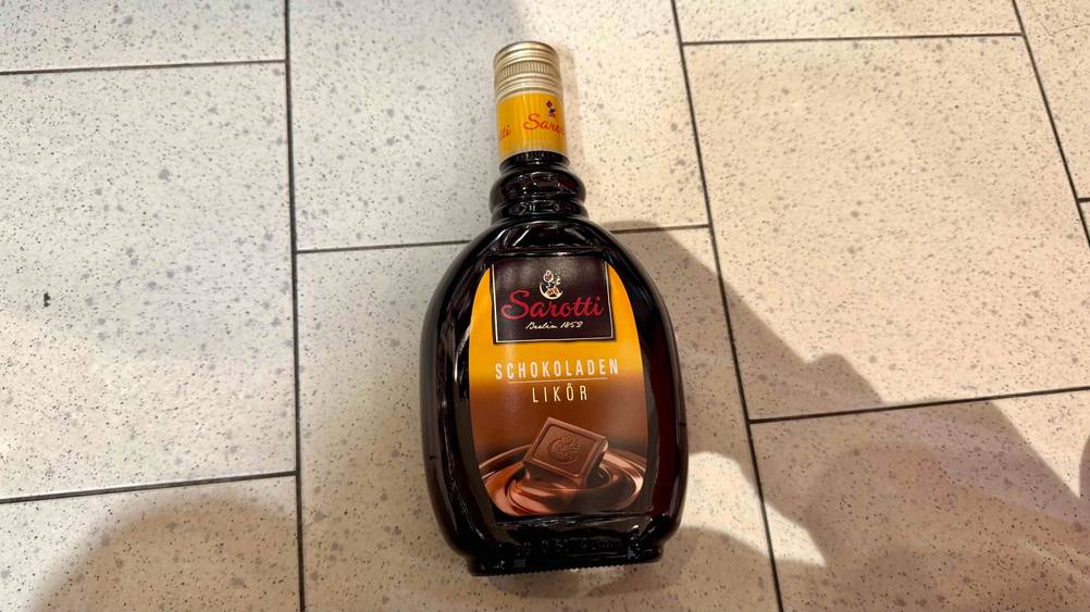Auf einem Fließenboden liegt eine Flasche des getesteten Schokoladenlikörs.