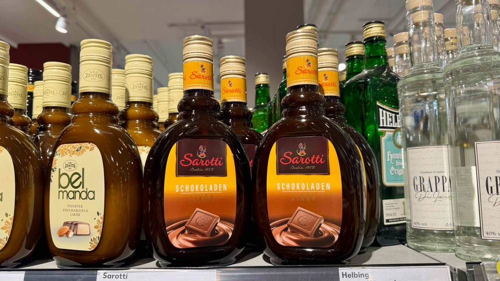 Mehrere Flaschen des Schokoladenlikör im Test in einem Verkaufsregal neben anderen Produkten.