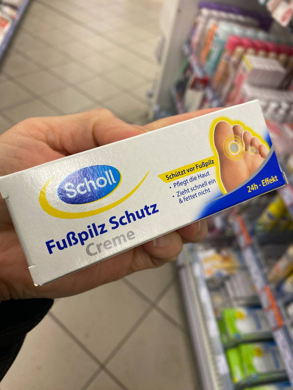 Eine Hand hält die Packung einer getesteten Fußpilz-Creme.